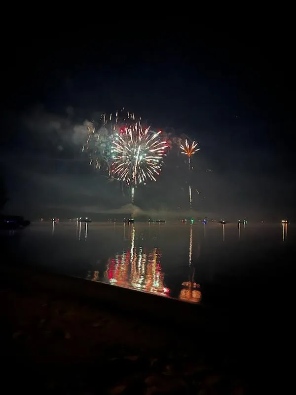 Red, green and white fireworks with colorful reflections on Lake Arbutus.